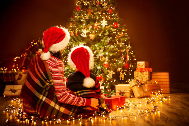 vista posteriore della famiglia di natale guardando l'albero di natale, madre bambina con cappello rosso - christmas family child christmas tree foto e immagini stock