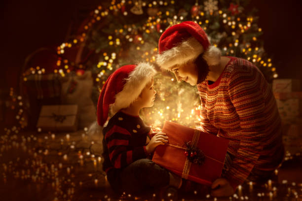 familie öffnen weihnachtsgeschenk beleuchtung vorhanden, weihnachtsbaum und glückliche mutter-baby - weihnachten familie stock-fotos und bilder