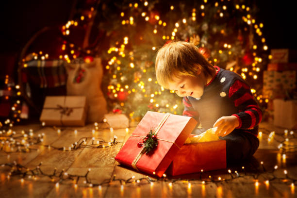 noël enfant ouvert present gift, heureux petit garçon à la recherche à la lumière de la magie en boîte, de chevreaux et d’arbre de noël - cadeaux de noël photos et images de collection