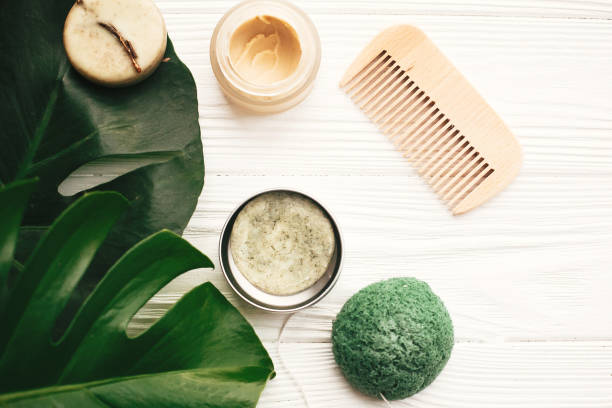 istock Zero waste flat lay. Natural eco friendly solid shampoo bar, wooden brush,  conditioner,soap, konjaku sponge on white wood with green monstera leaves.  Eco products plastic free 1063240892