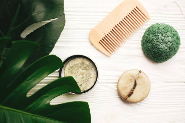istock Zero waste flat lay. Natural eco friendly solid shampoo bar, wooden brush,  conditioner,soap, konjaku sponge on white wood with green monstera leaves.  Eco products plastic free 1063240920