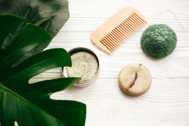 istock Zero waste concept. Natural eco friendly solid shampoo bar, wooden brush,  conditioner,soap, konjaku sponge on white wood with green monstera leaves.  Eco products plastic free 1063242034