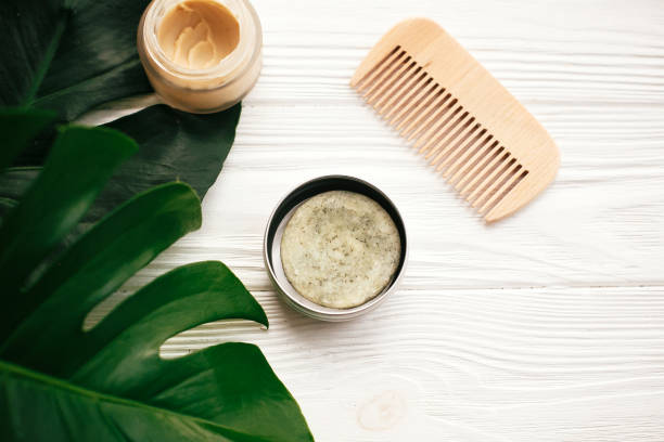 istock Zero waste concept. Natural eco friendly solid shampoo bar, wooden brush,  conditioner,soap, deodorant cream on white wood with green monstera leaves.  Eco products plastic free 1063242150