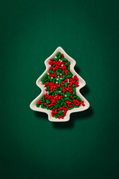 istock Some colored Christmas small candies in a Christmas tree shaped dish on a dark green background paper. 1063257830