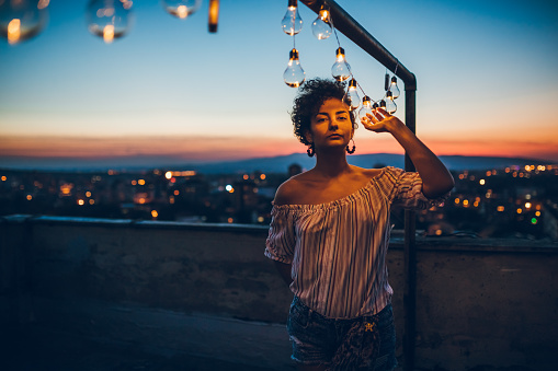 Young woman posing with string light on a rooftop