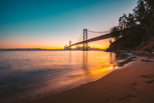 сан-франциско горизонта с окленд бэй мост в сумерках, калифорния, сша - golden gate bridge bridge night sunset стоковые фото и изображения