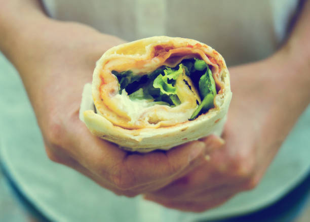 istock Woman holding sandwich wrap with ham, cheese and lettuce. 1063268332