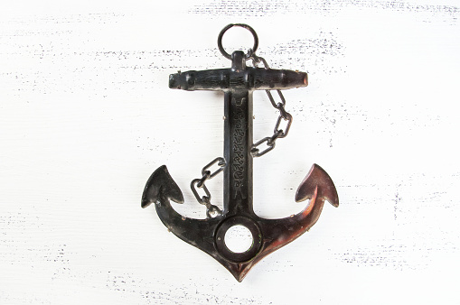 Vintage brass anchor on shabby white wooden background. Copy space for text.