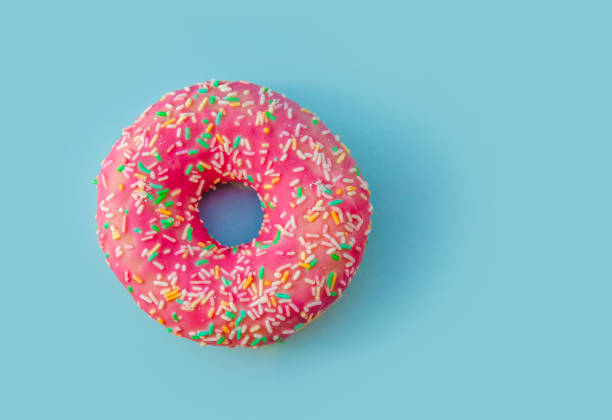 istock Tasty pink multi-colored donut on blue background isolated top view 1063275402