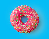 Tasty pink multi colored donut on a blue background isolated top view