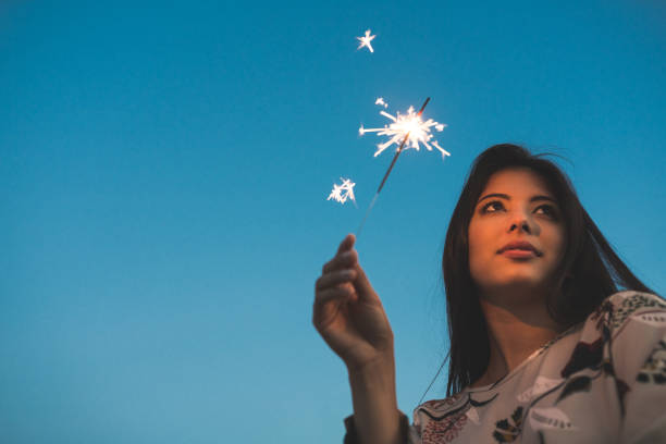 istock Woman outdoors holding a sparkler against sky 1063282244