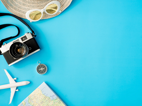 top view travel concept with retro camera films, map, passport, smartphone on blue background with copy space, Tourist essentials, vintage tone effect