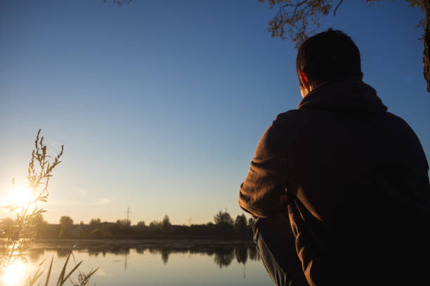 istock Young man sitting at sunset by the river alone 1063290192
