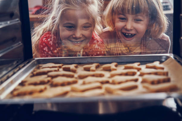 little girls waiting for christmas cookies to bake in the oven - little cakes imagens e fotografias de stock