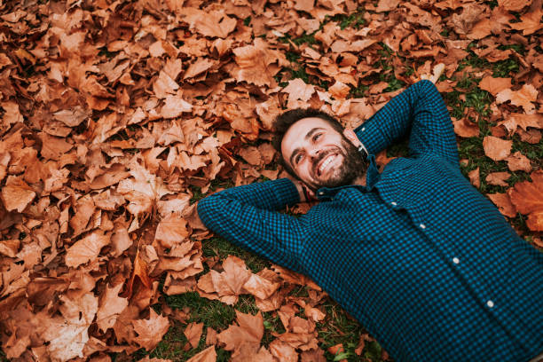 istock Young man lying down on the ground covered in autumn leaves 1063294032