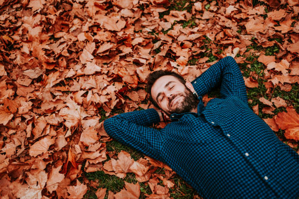 istock Young man lying down on the ground covered in autumn leaves 1063294034