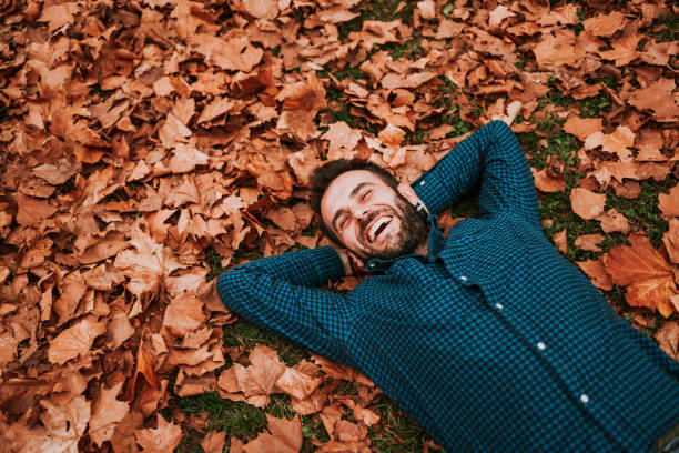istock Young man lying down on the ground covered in autumn leaves 1063294038