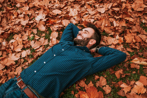 istock Young man lying down on the ground covered in autumn leaves 1063294040