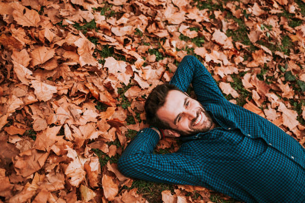 istock Young man lying down on the ground covered in autumn leaves 1063294048