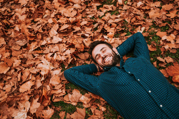istock Young man lying down on the ground covered in autumn leaves 1063294058