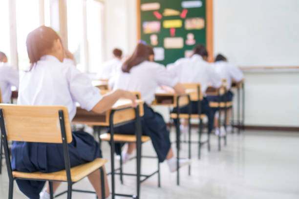 istock Exam for Education uniform students testing exams with pencil for multiple-choice quizzes or test answer sheets exercises in school rows chairs at classroom in Thailand, Behind Asian back to school 1063294424