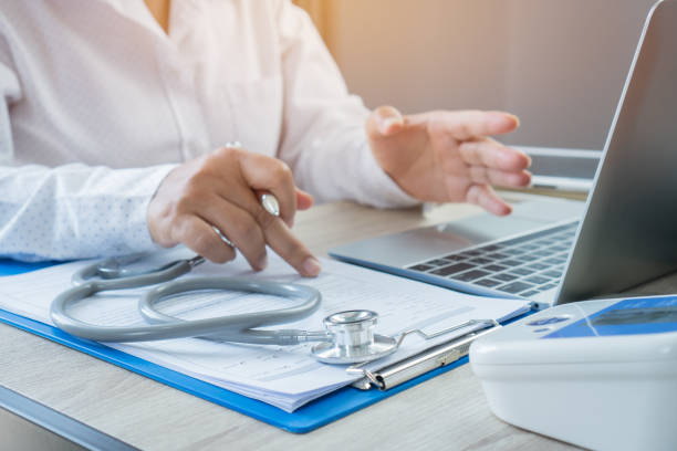 istock Medicine doctor hand explaining for patient at consulting room, working on laptop computer on desk in clinic, Focus stethoscope on foreground table in hostpital. Healthcare and medical concept. 1063294454