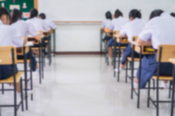 Exam for Education uniform students testing exams with pencil for multiple-choice quizzes or test answer sheets exercises in school rows chairs at classroom in Thailand, Behind Asian back to school