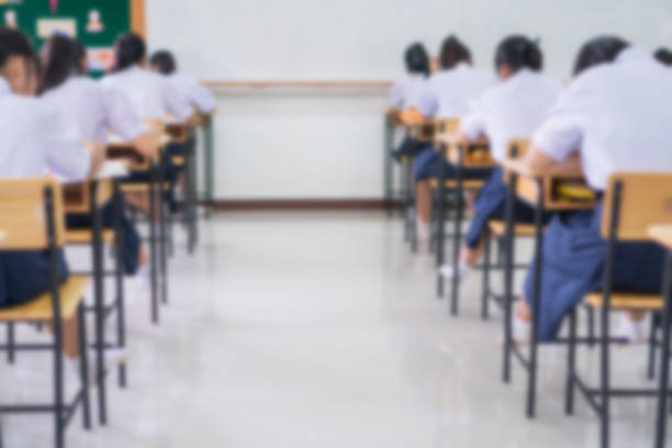 Exam for Education uniform students testing exams with pencil for multiple-choice quizzes or test answer sheets exercises in school rows chairs at classroom in Thailand, Behind Asian back to school stock photo