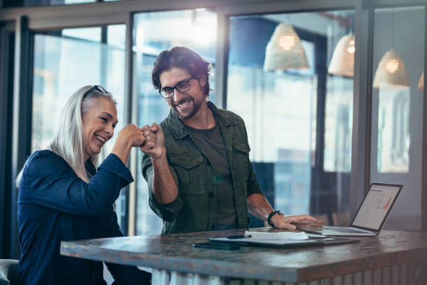 colegas de trabalho, fazendo um punho solavanco no escritório - business success - fotografias e filmes do acervo