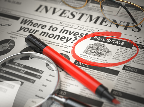 Real Estate is a best option to invest. Where to Invest concept, Investmets newspaper with loupe and marker.