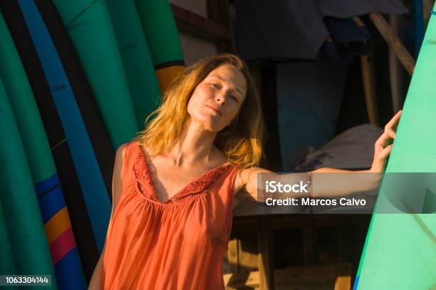 Head And Shoulders Portrait Of Young Beautiful And Happy Blond Woman Smiling Relaxed And Cheerful Posing With Colorful Surf Boards Leaning In Surfboard In Beauty Fashion Summer Concept Stock Photo - Download Image Now
