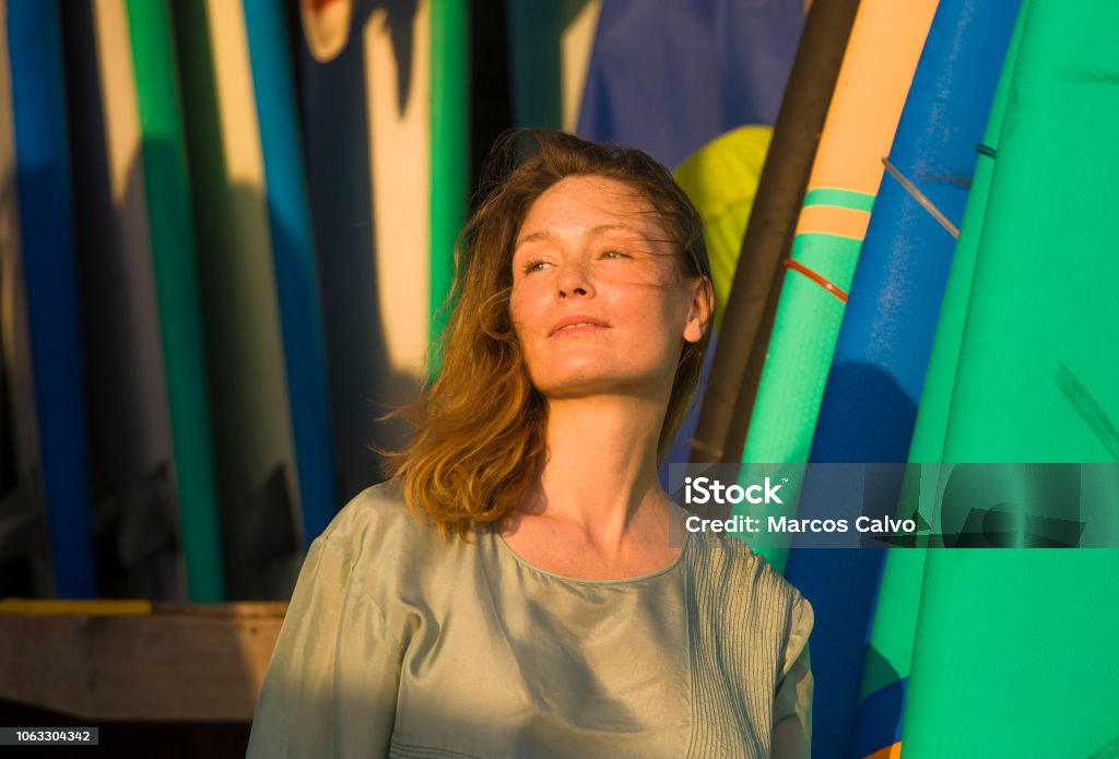 head and shoulders portrait of young beautiful and happy blond woman smiling relaxed and cheerful posing with colorful surf boards in the background in beauty fashion and summer holidays concept 30-39 Years Stock Photo