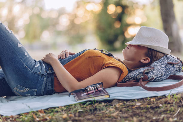 One woman, beautiful young woman lying on a meadow in nature alone and sleeping.