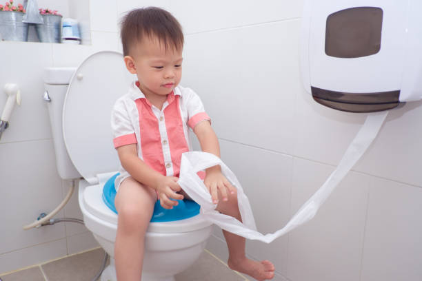 cute smiling little asian 2 year old toddler baby boy child sitting on toilet modern style with a kid bathroom accessory - people purity personal accessory handkerchief imagens e fotografias de stock