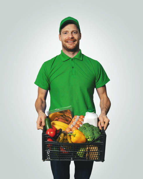 entrega de comestibles - hombre en uniforme con la caja de alimento verde - box men holding isolated fotografías e imágenes de stock