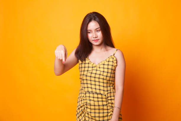 istock Beautiful young Asian woman point down to blank space. 1063328812