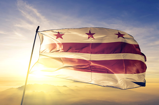 Washington DC of United States flag on flagpole textile cloth fabric waving on the top sunrise mist fog