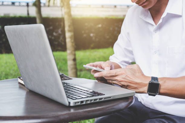 istock Image of businessman working with laptop and analysis financial document data on smartphone in outdoor office, finance,investment, business concept and Accounting,Economic,commercial 1063342288