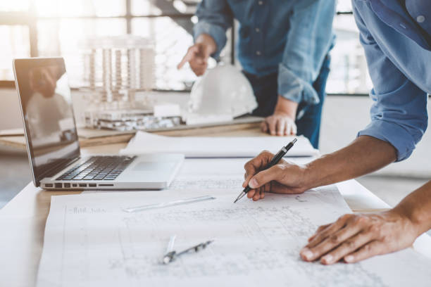 istock Construction concept of Engineer or architect meeting for project working with partner and engineering tools on model building and blueprint in working site 1063344060