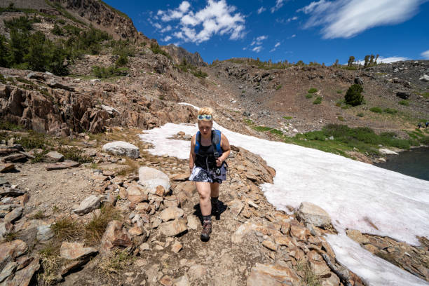 female hiker looking distressed after hiking through a small snow field in the eastern sierra california - saddlebag imagens e fotografias de stock