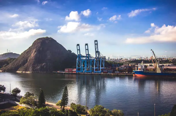 Commercial port of the city of Vitória in Brazil. Landscape that blends the nature and artificialities of cargo transport cranes.