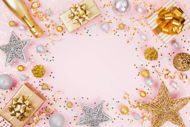 istock Christmas background with gift or present box, champagne, confetti and holiday decorations on pink pastel table top view. 1063365466