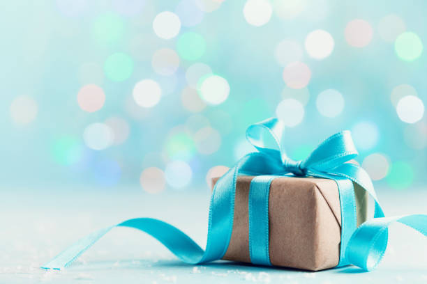 istock Christmas gift box against blue bokeh background. Holiday greeting card. 1063366942