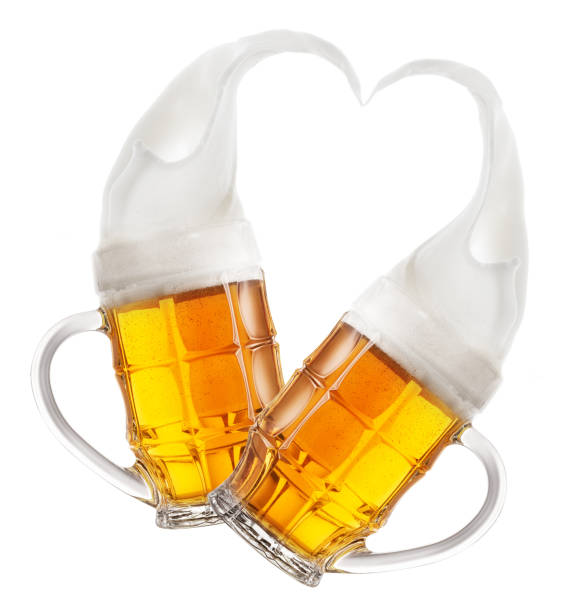 Two faceted mugs of beer with splashes of foam in shape of heart stock photo