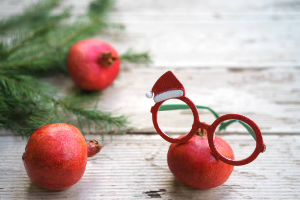 vives rouge noël grenades lunettes lunettes avec cadre décoratif de vacances et de branches d’arbres sapin sur fond en bois gris rustique. noël nouvel an dépliez votre concept yeux piquer. espace copie - noble fir photos et images de collection