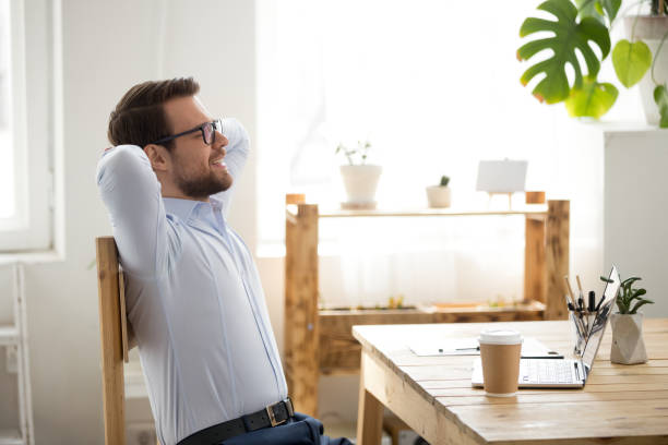 istock Relaxed man sitting holding hands behind head indoors 1063372148