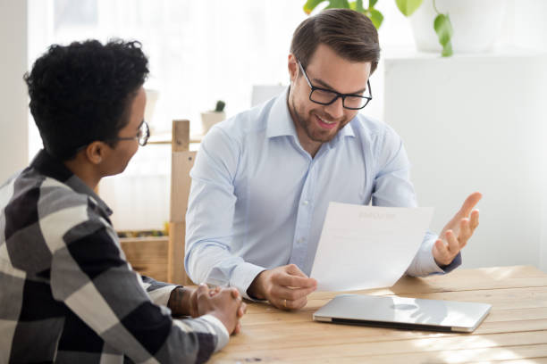 istock Smiling boss holding cv interviewing black woman 1063372252