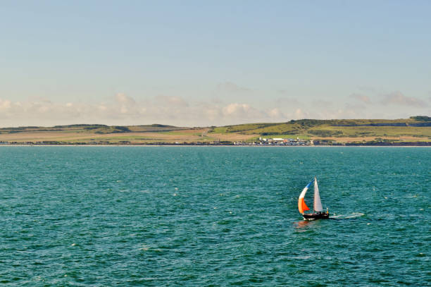 istock Sailing boat is moving along the seashore in a sunny summer day. 1063372600