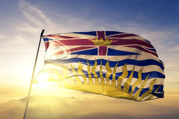 Photo of British Columbia province of Canada flag textile cloth fabric waving on the top sunrise mist fog
