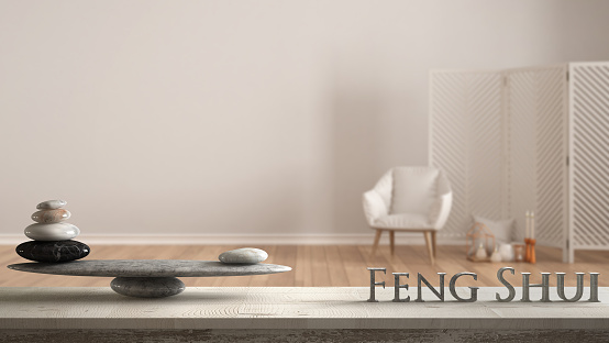 Wooden vintage table shelf with stone balance and 3d letters making the word feng shui over white background with armchair, screen, candles and decor, zen concept interior design